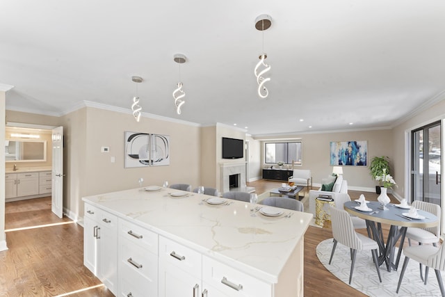kitchen featuring light stone countertops, light wood-style flooring, a kitchen island, and white cabinetry