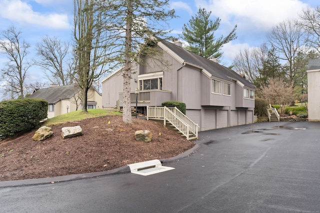 view of front of property with a chimney, stairway, aphalt driveway, and a garage