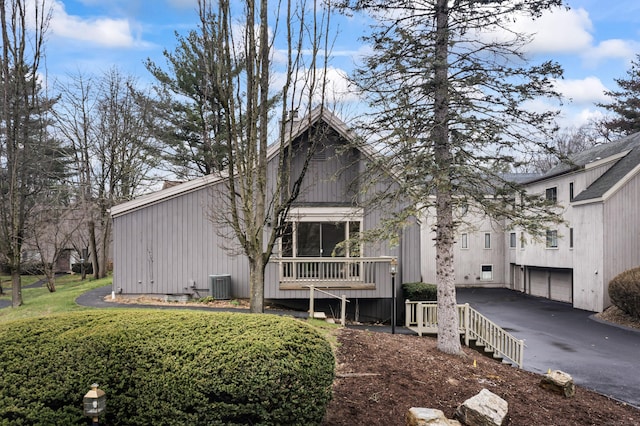 back of house with central AC, aphalt driveway, and a garage