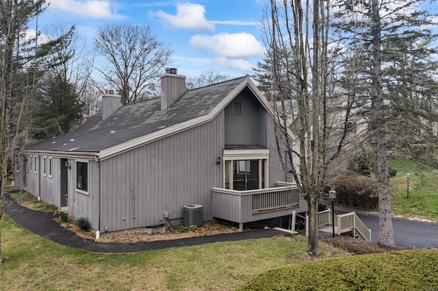 view of side of home featuring a chimney, central AC unit, a yard, a wooden deck, and roof with shingles