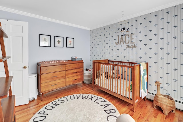 bedroom featuring crown molding, wood-type flooring, and a nursery area