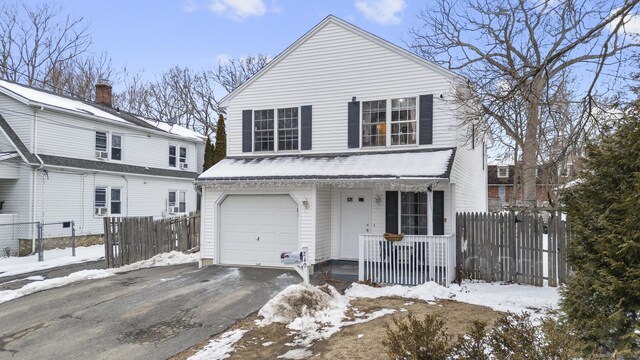 view of front facade with an attached garage, fence, and aphalt driveway