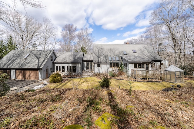 view of front of house with a garage, a porch, a greenhouse, a chimney, and an outdoor structure
