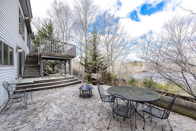 view of patio featuring stairs, outdoor dining area, a fire pit, and a deck
