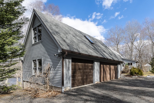 view of side of property featuring a garage and a shingled roof