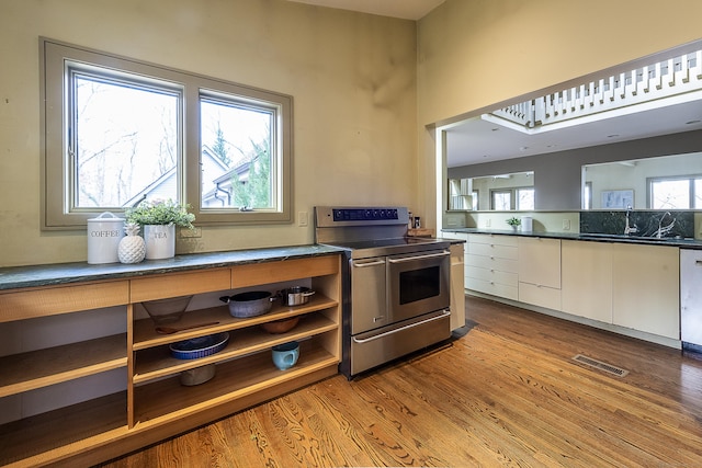 kitchen featuring white cabinets, dark countertops, appliances with stainless steel finishes, wood finished floors, and visible vents