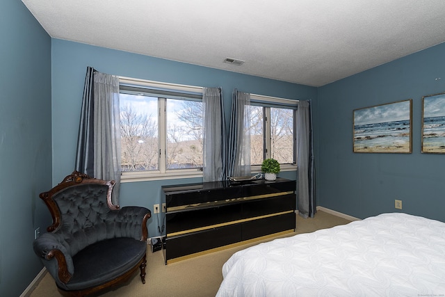 bedroom with carpet floors, baseboards, a textured ceiling, and visible vents