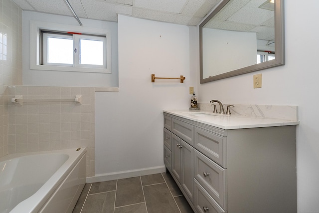 full bathroom with baseboards, a paneled ceiling, tile patterned floors, and vanity