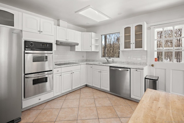 kitchen featuring sink, light tile patterned floors, stainless steel appliances, tasteful backsplash, and white cabinets