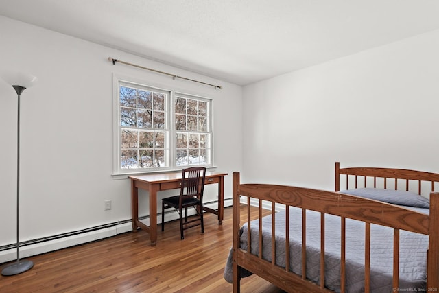 bedroom featuring baseboard heating and wood-type flooring