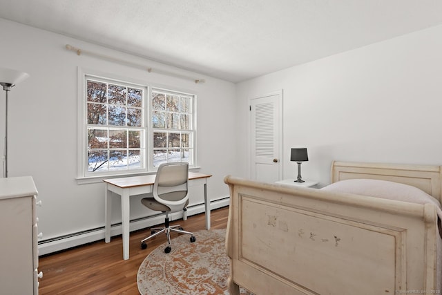 bedroom with hardwood / wood-style flooring, a baseboard radiator, and a textured ceiling