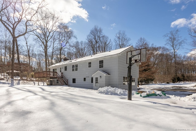 snow covered back of property featuring a wooden deck