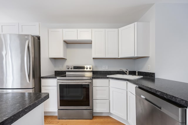 kitchen featuring white cabinetry, appliances with stainless steel finishes, sink, and dark stone counters