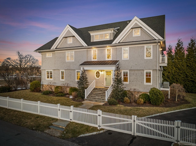 shingle-style home with a fenced front yard and a gate