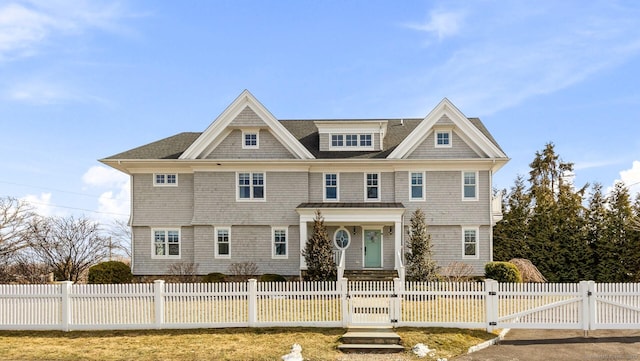 shingle-style home with a fenced front yard and a gate