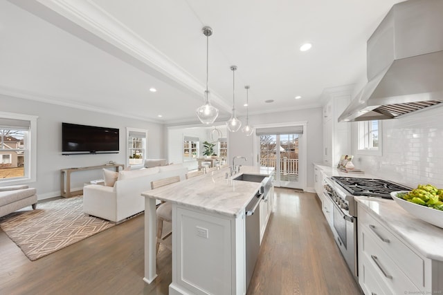 kitchen featuring stainless steel appliances, white cabinets, backsplash, wall chimney exhaust hood, and crown molding