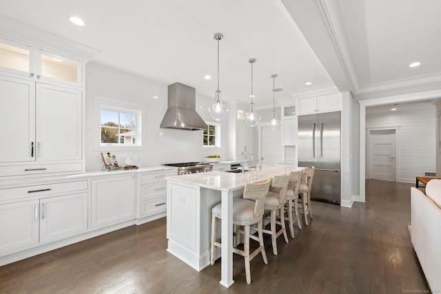 kitchen with wall chimney range hood, dark wood-style flooring, stainless steel built in refrigerator, and range