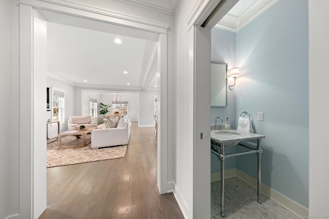 bathroom with baseboards, hardwood / wood-style flooring, ornamental molding, a sink, and recessed lighting