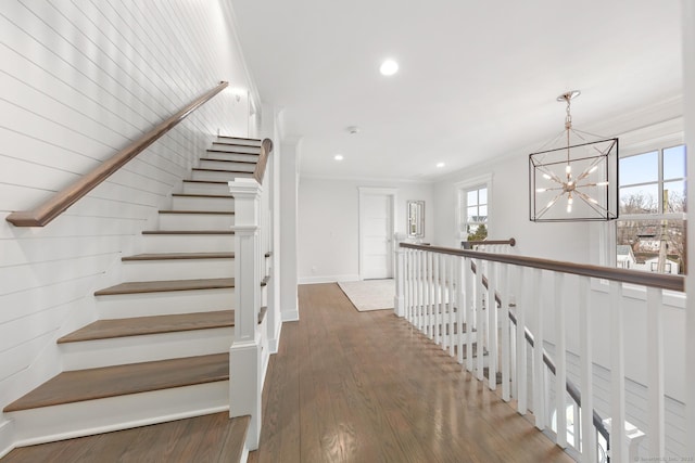 stairs featuring baseboards, ornamental molding, wood finished floors, a notable chandelier, and recessed lighting