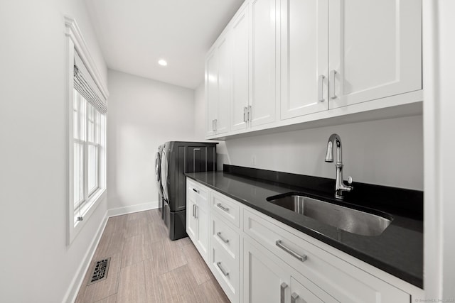 kitchen with dark countertops, visible vents, a sink, and white cabinetry