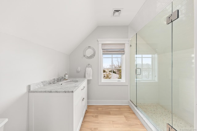 bathroom with baseboards, visible vents, wood finished floors, vaulted ceiling, and a shower stall