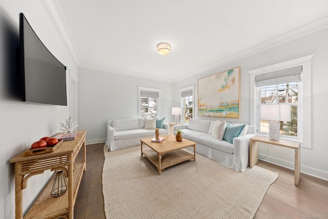 living area with baseboards, light wood finished floors, crown molding, and a healthy amount of sunlight