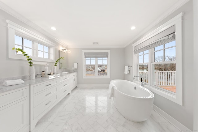 bathroom with visible vents, baseboards, crown molding, vanity, and a freestanding tub