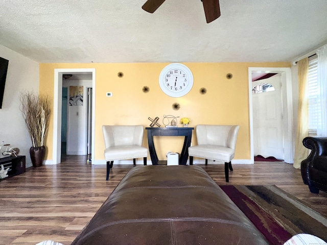 living room with hardwood / wood-style flooring, ceiling fan, and a textured ceiling