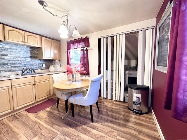 kitchen featuring light brown cabinetry, wood-type flooring, sink, a chandelier, and hanging light fixtures