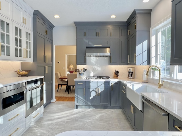 kitchen featuring sink, gray cabinetry, ventilation hood, appliances with stainless steel finishes, and decorative backsplash