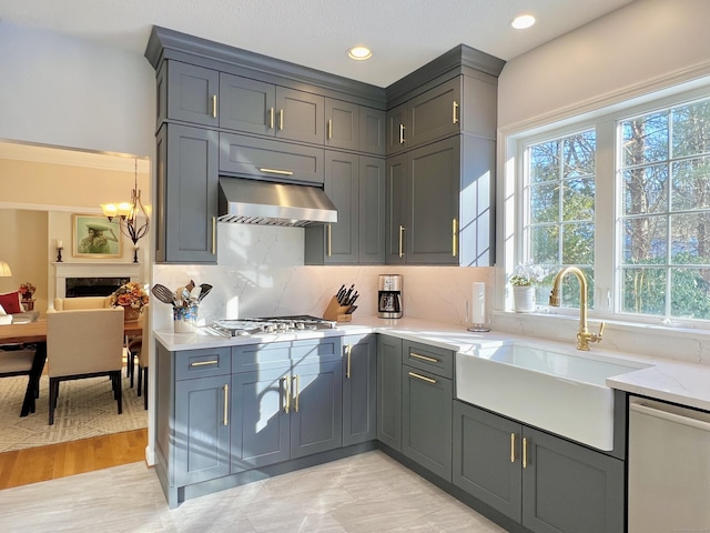 kitchen featuring sink, stainless steel appliances, tasteful backsplash, light stone counters, and ventilation hood