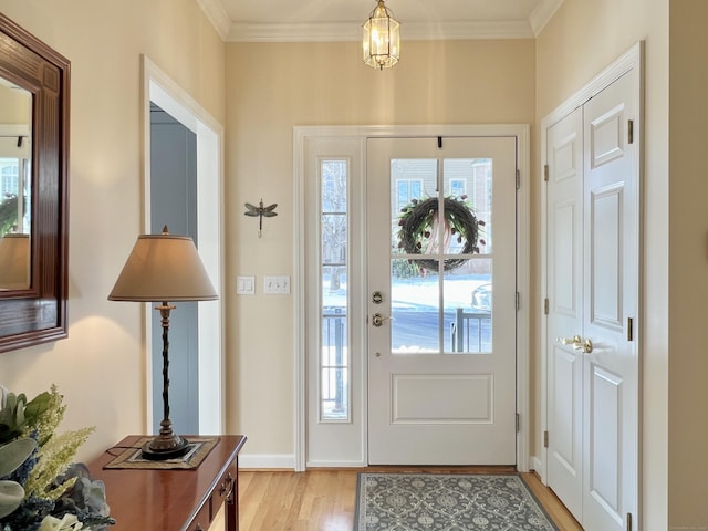 foyer entrance with ornamental molding and light hardwood / wood-style floors