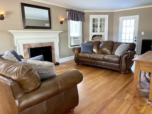 living room featuring crown molding, radiator heating unit, a high end fireplace, and light wood-type flooring