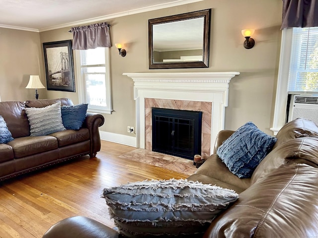 living room with cooling unit, crown molding, a premium fireplace, and light wood-type flooring