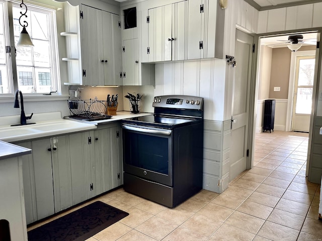 kitchen featuring sink, electric range, light tile patterned floors, and a healthy amount of sunlight