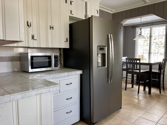 kitchen with white cabinetry, decorative backsplash, hanging light fixtures, stainless steel appliances, and crown molding