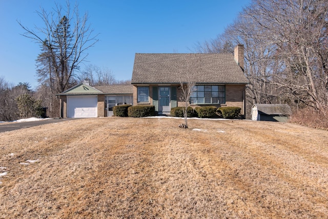 ranch-style house with a garage, roof with shingles, brick siding, and a chimney