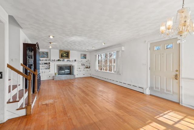 unfurnished living room with stairs, light wood finished floors, baseboard heating, and a fireplace