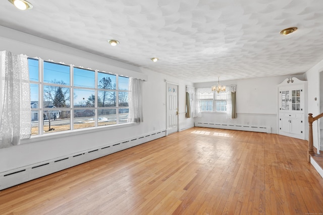 unfurnished room with a chandelier, a baseboard radiator, wood-type flooring, and a textured ceiling