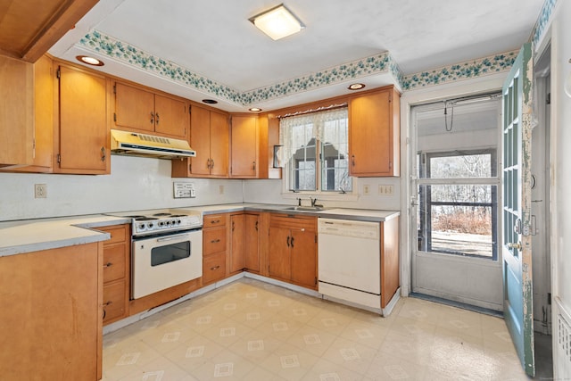 kitchen featuring under cabinet range hood, white appliances, a sink, a wealth of natural light, and light floors