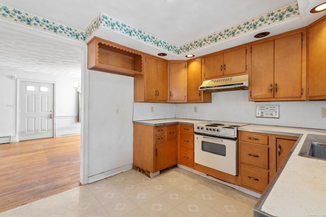 kitchen with white range with electric stovetop, brown cabinets, light countertops, under cabinet range hood, and a sink