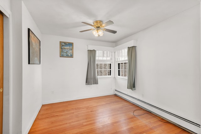 unfurnished room with a baseboard heating unit, ceiling fan, light wood finished floors, and baseboards