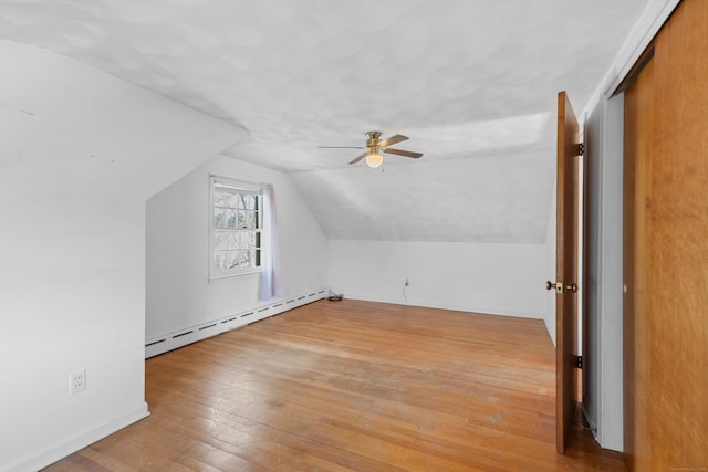 additional living space with lofted ceiling, ceiling fan, baseboard heating, and light wood-type flooring