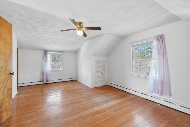 bonus room featuring lofted ceiling, wood-type flooring, a baseboard heating unit, and a ceiling fan