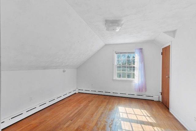 additional living space with lofted ceiling, baseboard heating, and hardwood / wood-style flooring