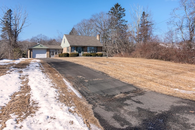 view of front of property featuring driveway, a garage, and a chimney