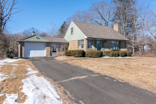 view of front of house with aphalt driveway, brick siding, a chimney, and an attached garage