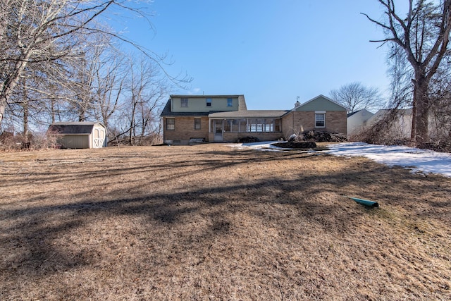 rear view of property with a storage shed, a yard, brick siding, and an outdoor structure