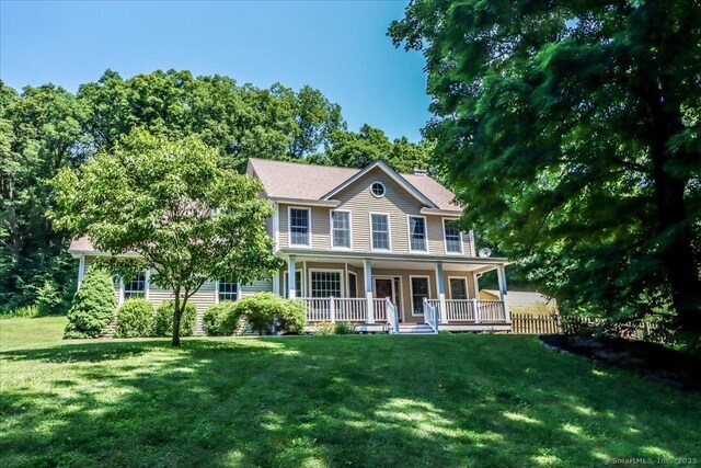 colonial home featuring covered porch and a front lawn