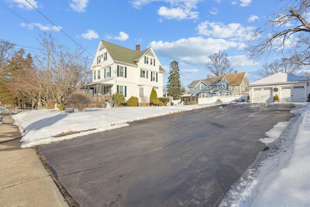 view of front of property featuring a garage, a residential view, a chimney, an outbuilding, and covered porch